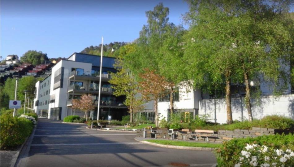 Bilde av Fyllingsdalen sykehjem med inngangsparti, grønne trær og benker