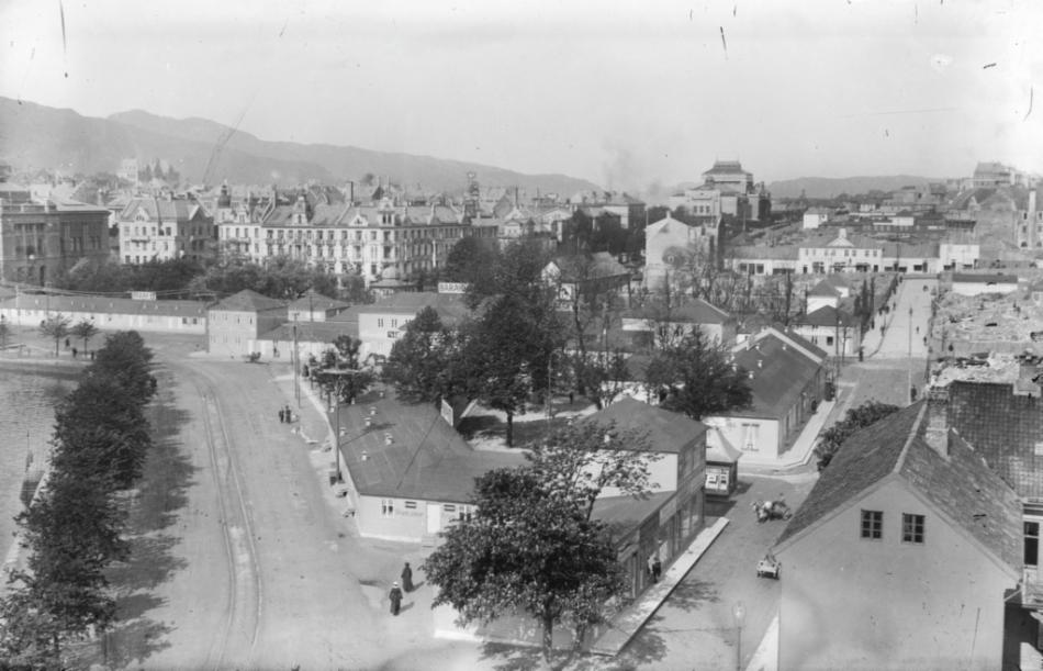 Bildet er av brakkebyen etter bybrannen, inkludert brakke E 61 som er hvor Bergesen hadde sin midlertidige butikk. Kaigaten er på høyre side i bildet, og ved Kaigaten, direkte bak den personen med hest og kjerre, ligger E brakkene. Fotograf: Atelier KK.  Spesialsamlingene ved Universitetsbiblioteket i Bergen