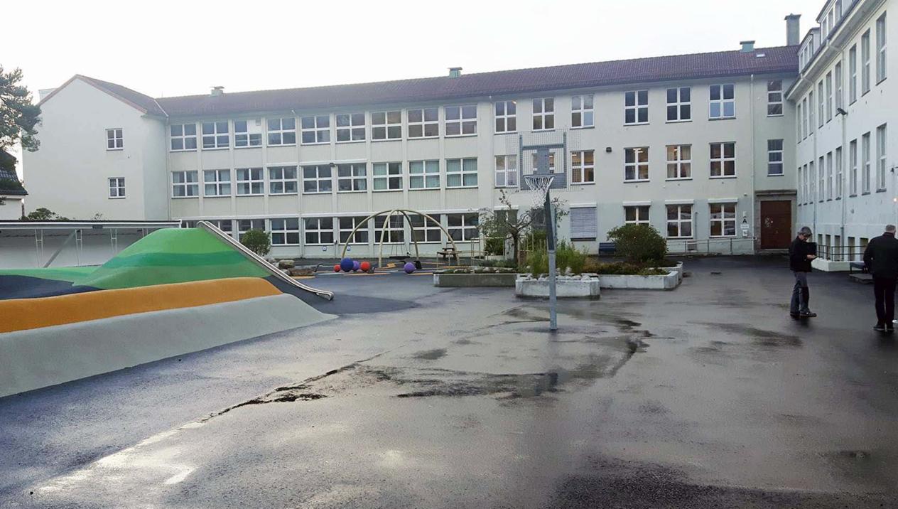 Hvit skolebygning på tre plan, bygget i vinkel.