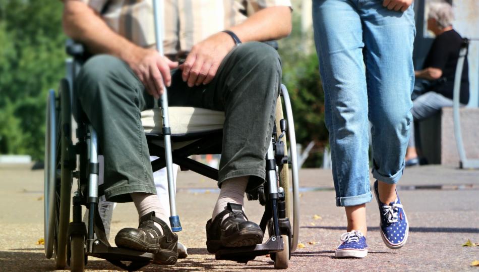 Bildet viser føtter til en som sitter i rullestol og en som går