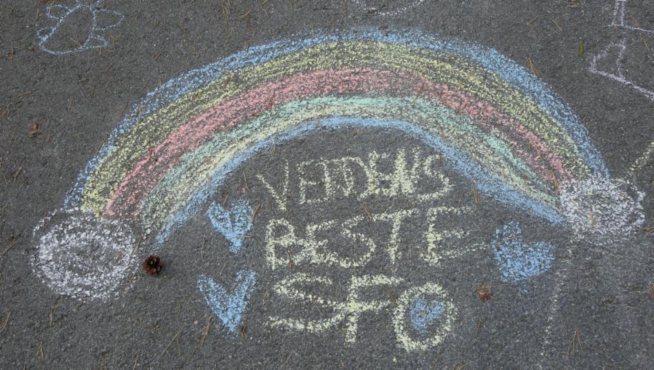Krittegning på asfalt med regnbue og 'verdens beste SFO'.