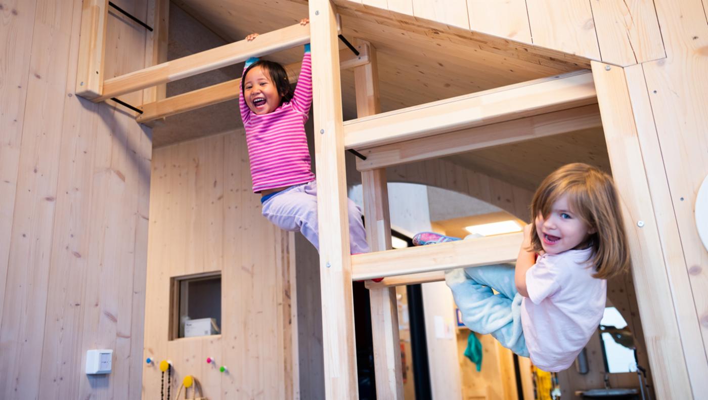 Et innvendig bilde av barn som klatrer på en trestruktur.