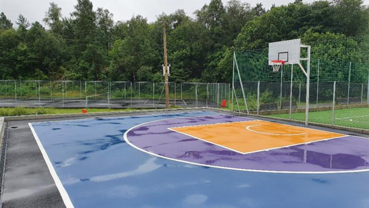 Basketballbane med dekke i blått, lilla og oransje.