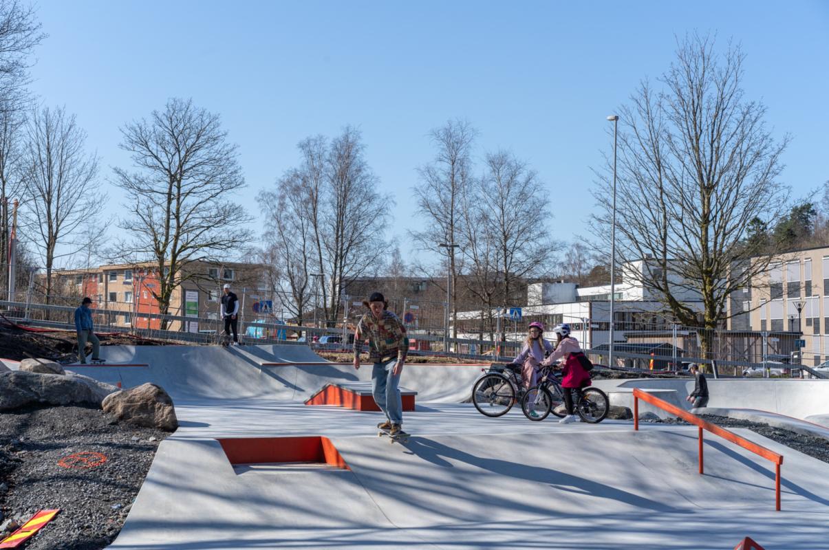 Ungdommer på sykkel og rullebrett i skateparken. 