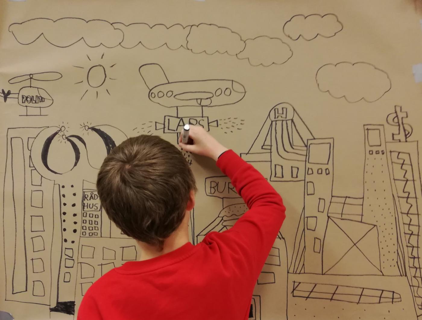 En gutt tegner på en vegg. 
