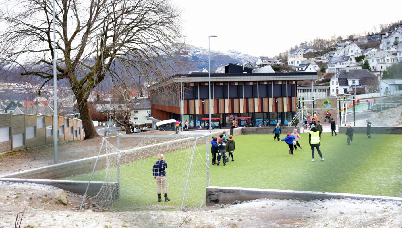 Barn leker på fotballbane utenfor skole