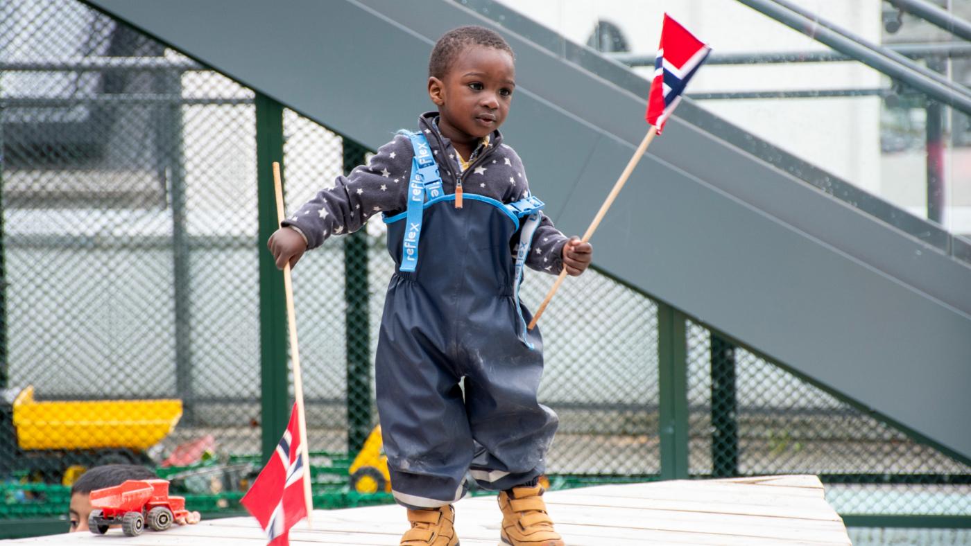 Gutt danser mens han holder to norske flagg 