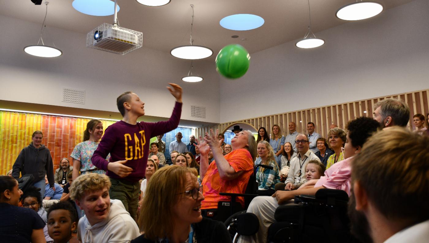 Publikum i sal med ballong som spretter rundt