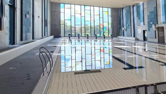 Bilde av innendørs svømmehall. I bakkant er det et fargerikt vindu.