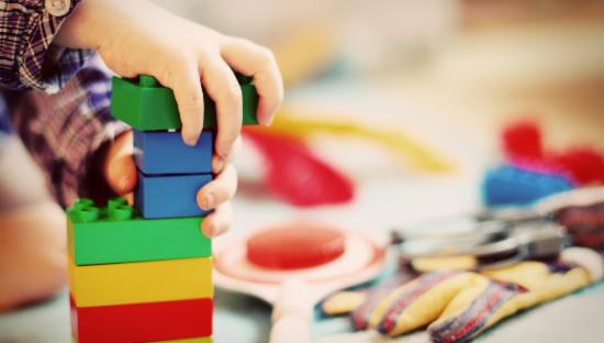 Barnehånd som bygger legoklosser