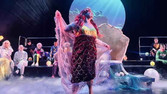 En jente står på scenen iført fargerikt havfruekostyme.