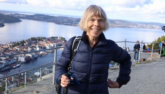 Eldre dame i turklær på Fløyen med Bergen i utsikt bak