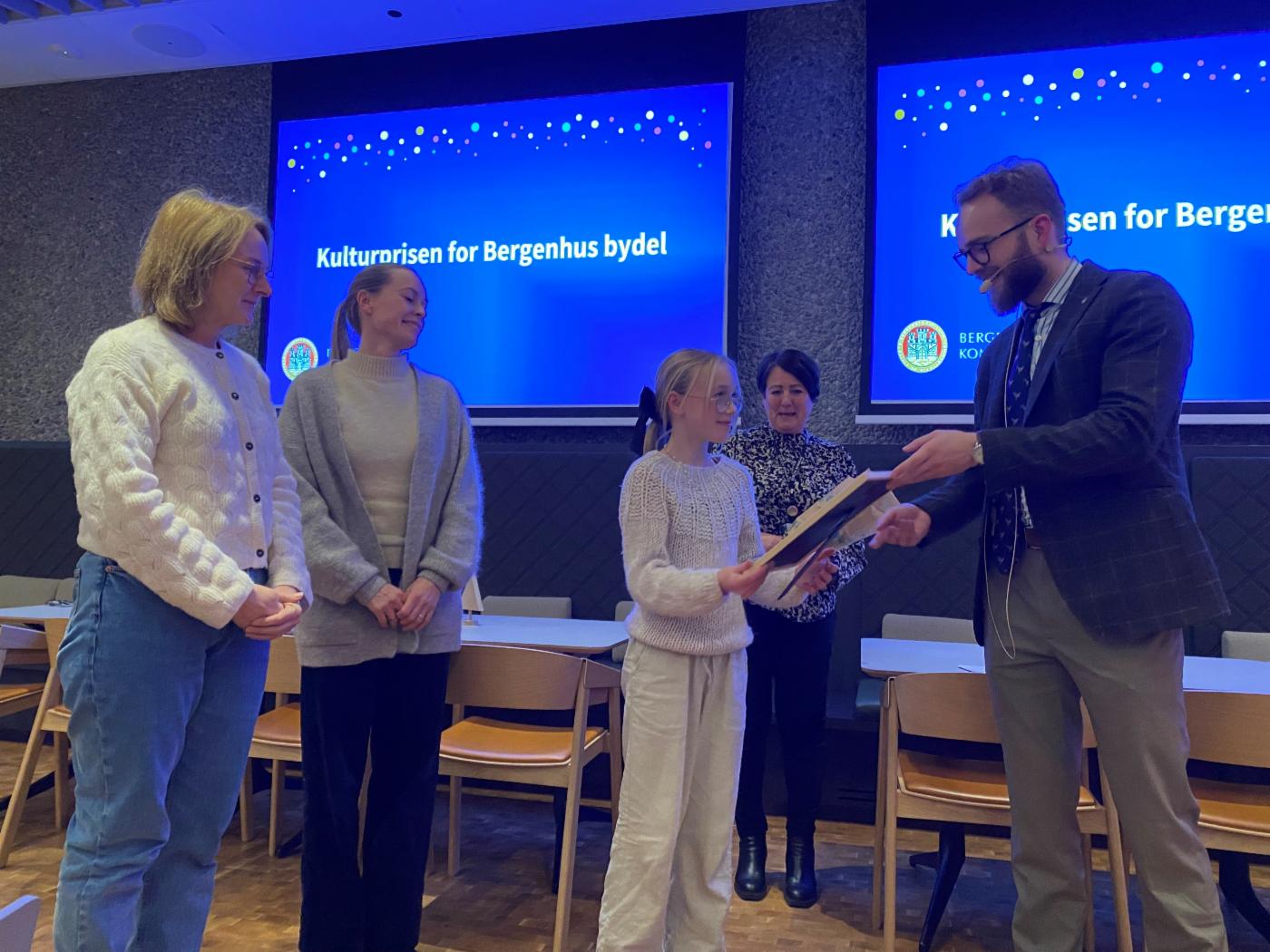 To voksne damer og en ung jente mottar pris fra byråd Reidar Digranes. 