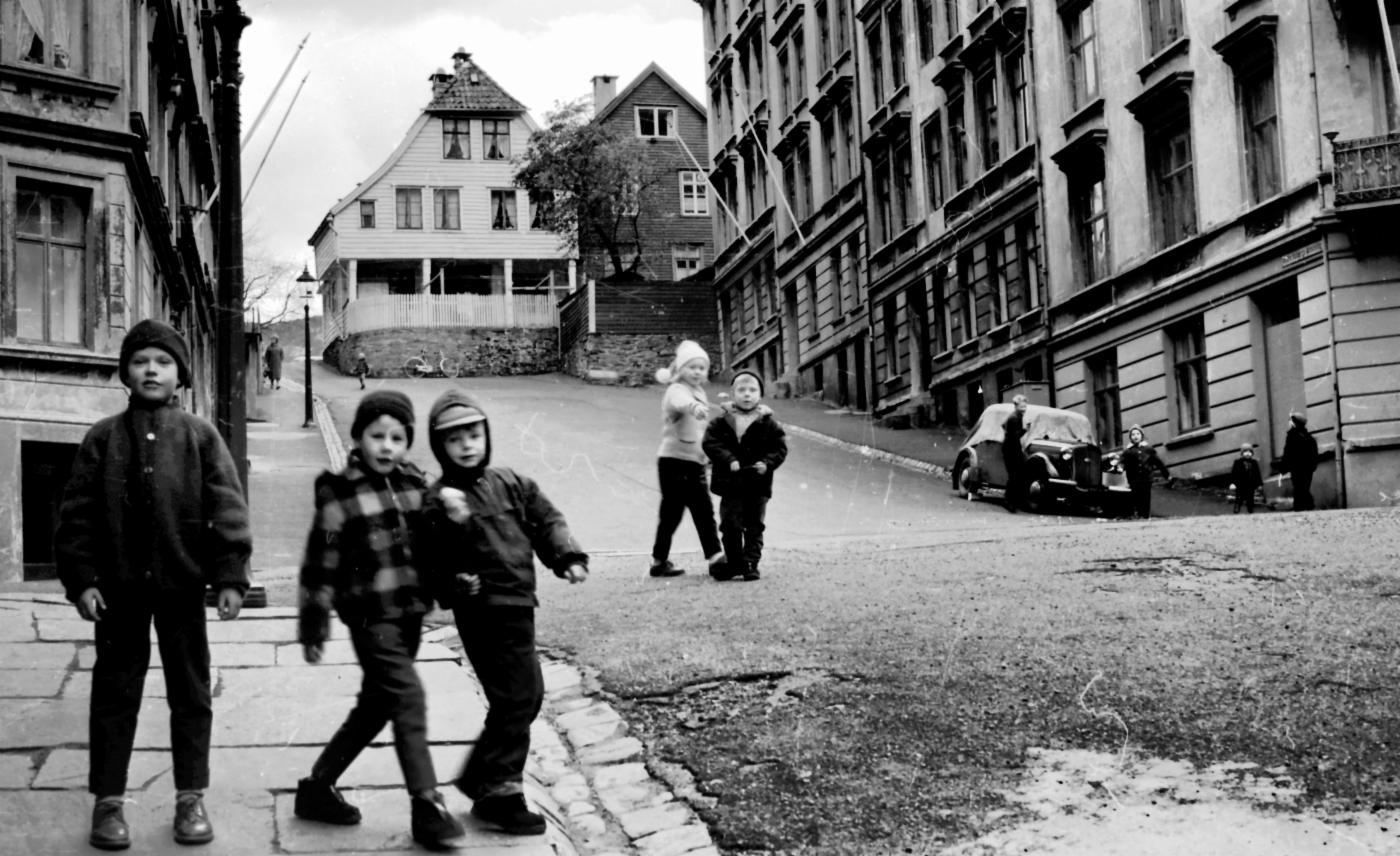 Svarthvitt-bilde fra bymiljø i Bergen. Barn kaster snøballer.