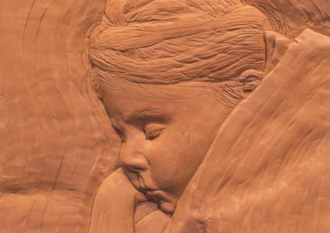 Et keramikkbilde/skulptur som viser en jente som sover. 