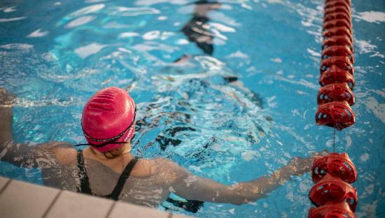 Jente med rosa badehette, i svømmebasseng