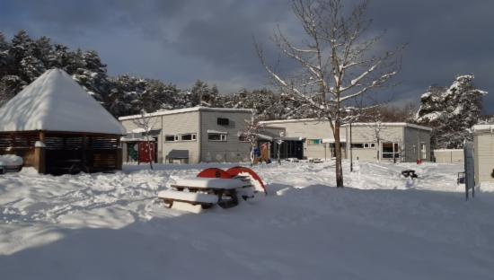 Bilde av uteområde med barnehagen i bakgrunnen, en nydelig vinterdag
