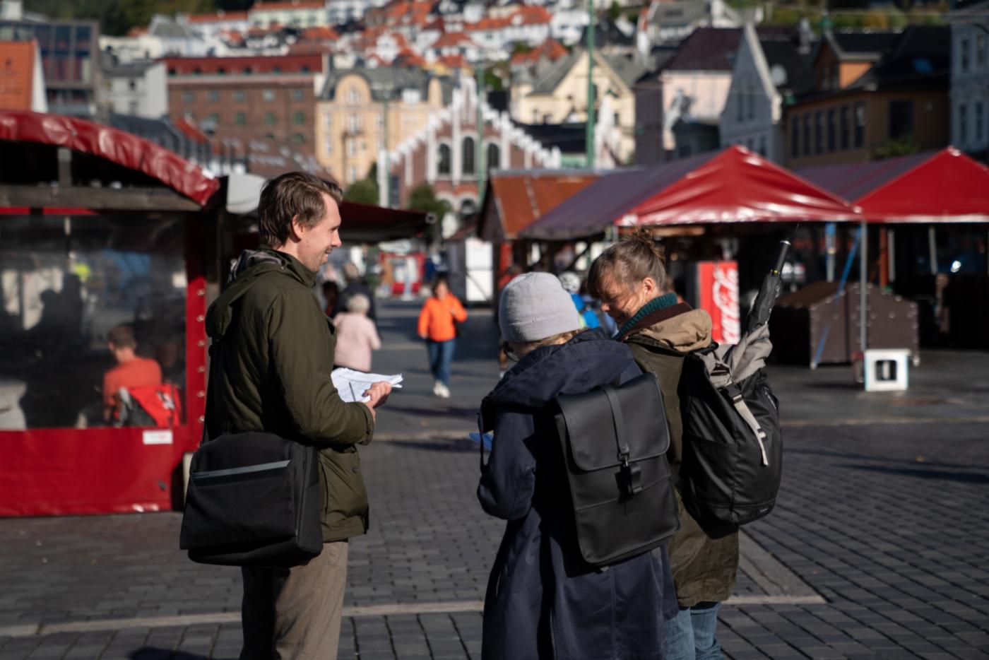En ansatt fra Bymiljøetaten intervjuer to forbipasserende på Torget. 