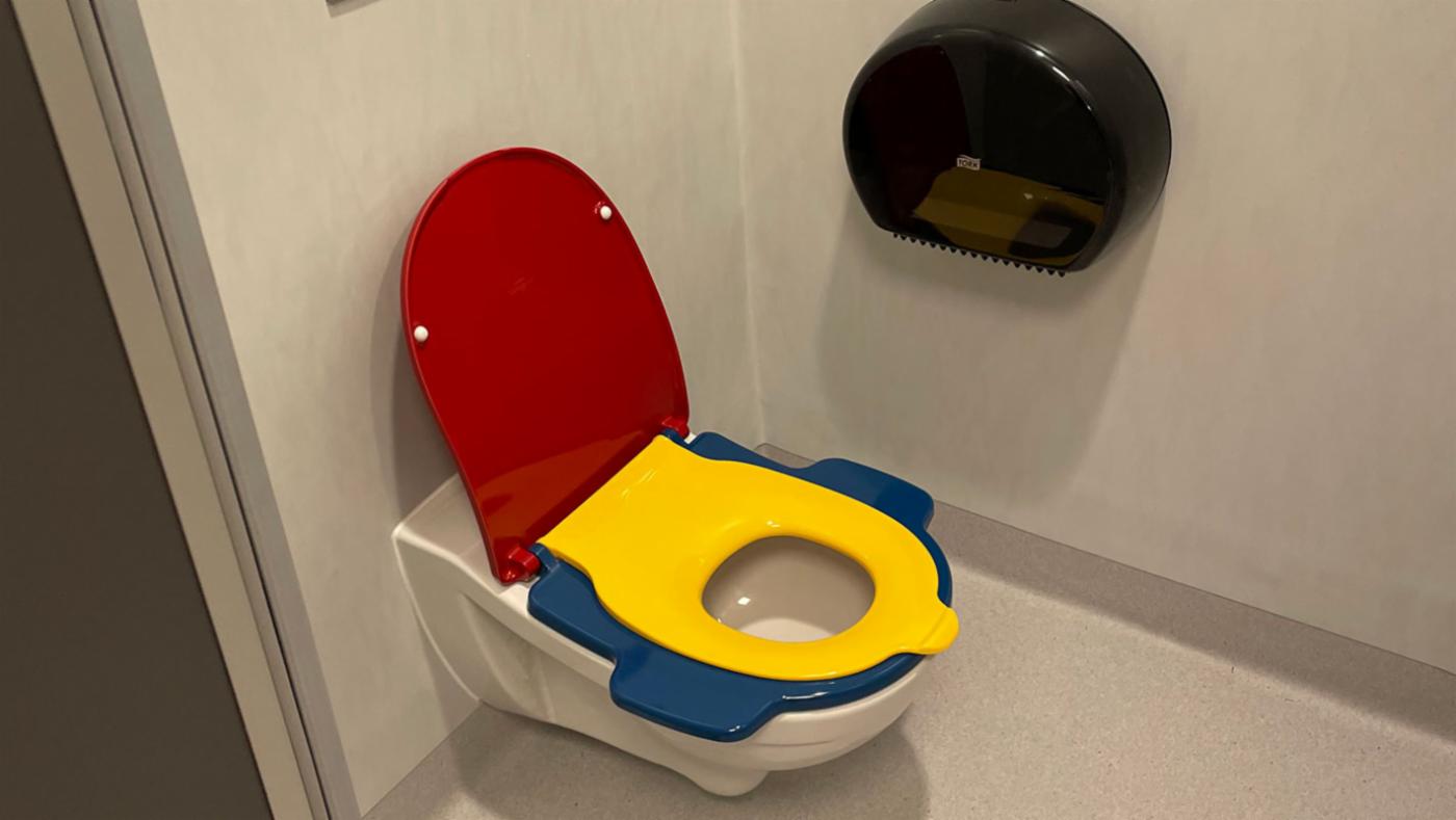 Lite toalett med to sete på, for små barn. Raudt tolokk.