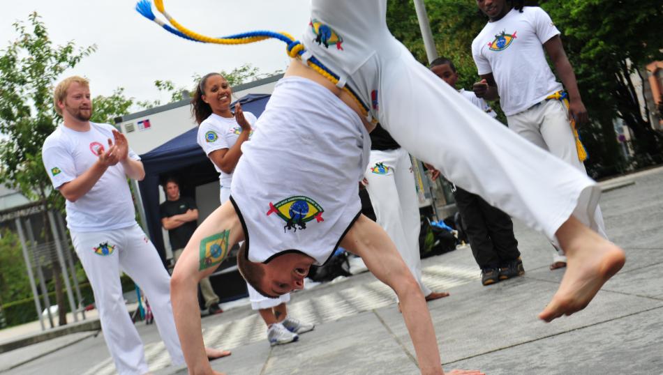 Ungdommer i hvite drakter som spiller capoeira.