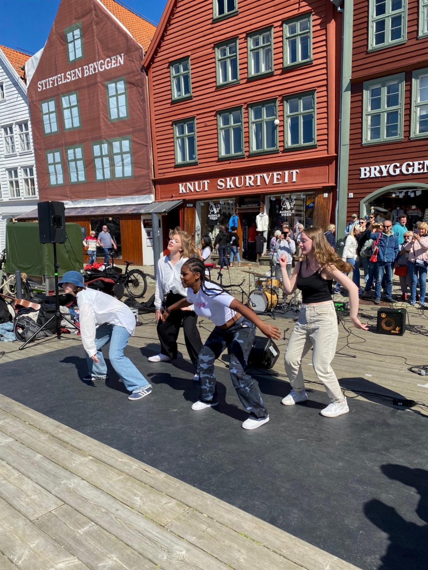 En gruppe jenter danser på Bryggen i Bergen. 