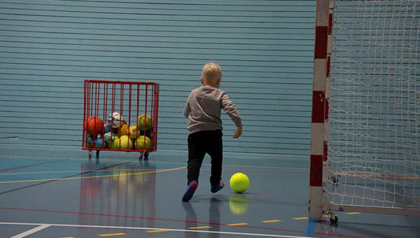  Liten gutt sparker ball inne i en hall.