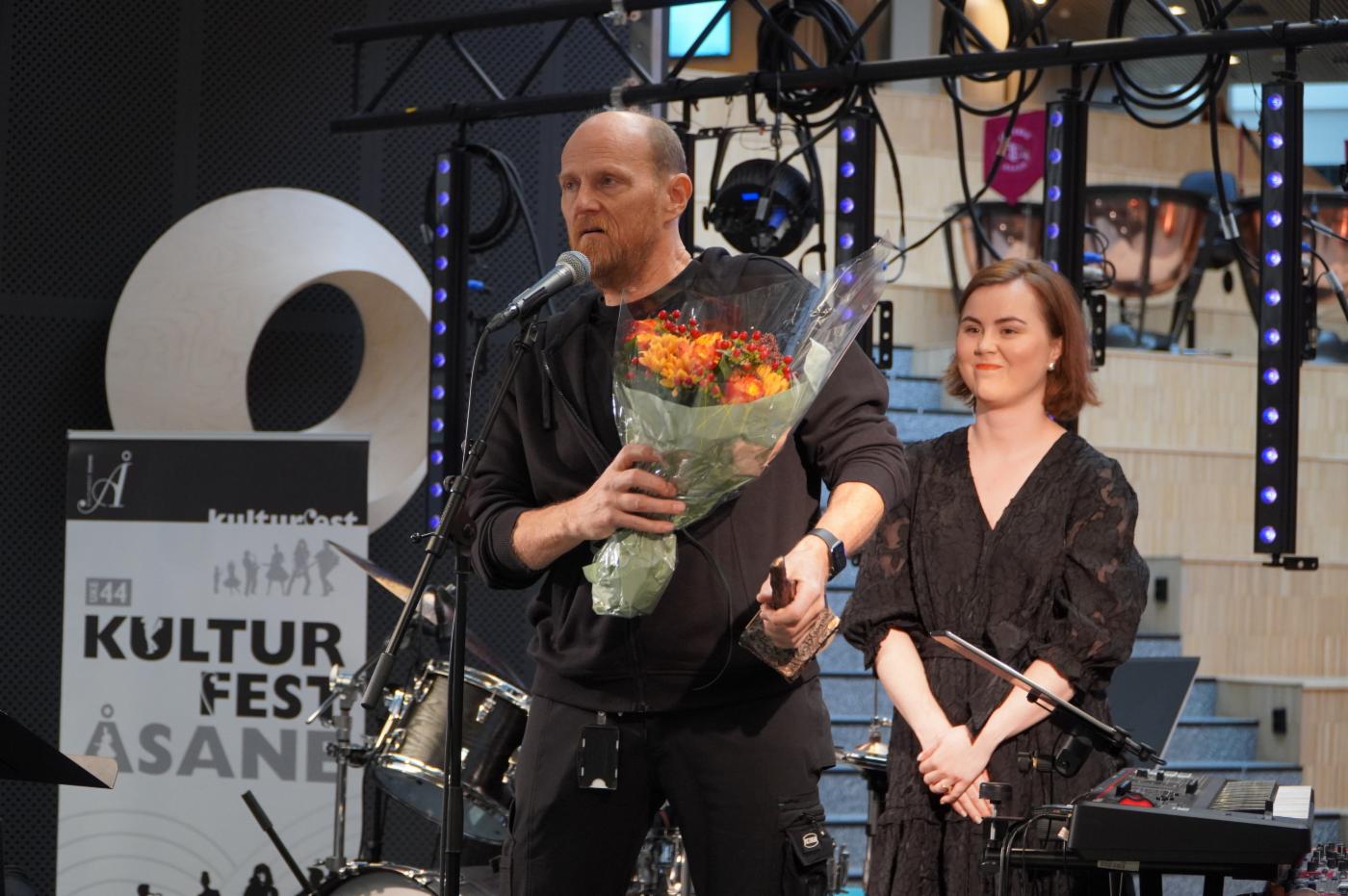 To mennesker på scenen tar i mot kulturprisen for åsane 2022. 